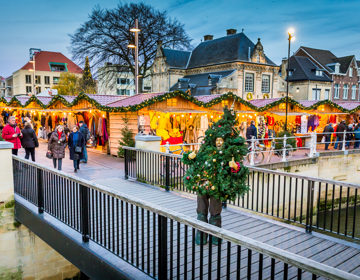 Als kerstboom verkleed persoon staat op het bruggetje voor Santa's Village