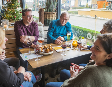 Vriendengroep zit rond een tafel waarop drankjes en fancy bitterballen staan