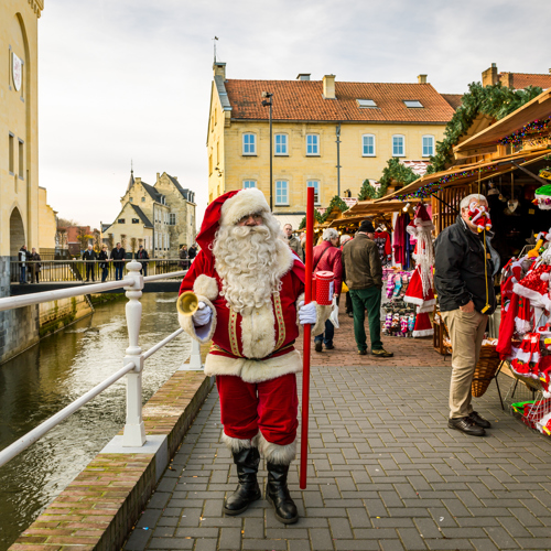 Kerstman loopt langs kerstkraampjes en Geul op Santa's Village