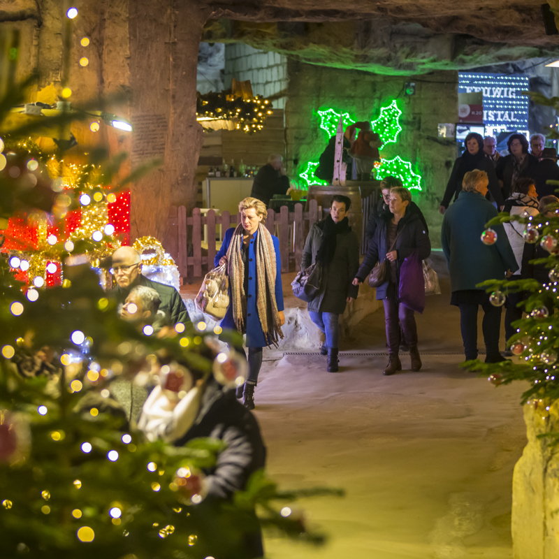 Een doorkijkje met shoppende mensen in een kerstversierde mergelgang