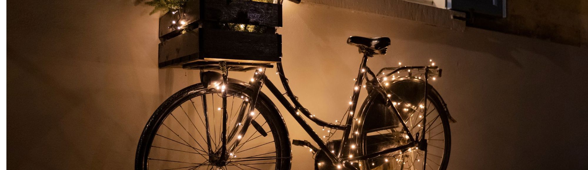 Fiets met kerstverlichting staat tegen gevel